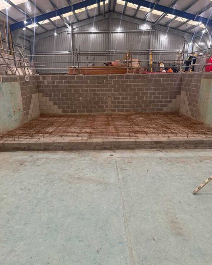 Construction site with a partially built stone wall and a concrete floor.
