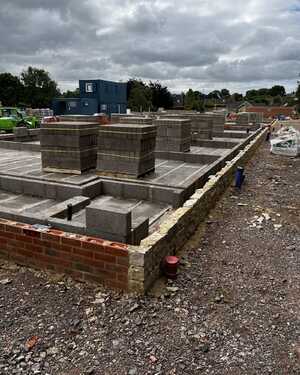 Construction site with brick and block foundations under a cloudy sky.