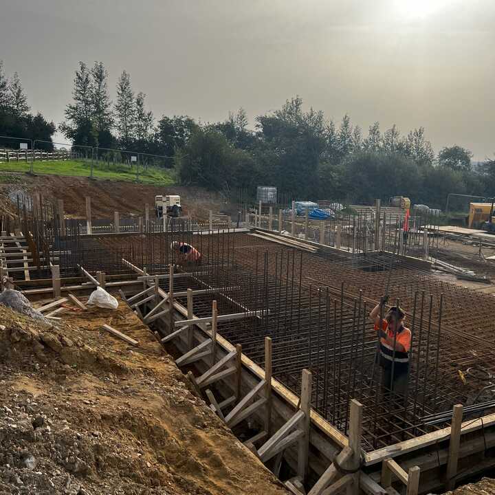 Construction site with foundation work and equipment, surrounded by buildings.