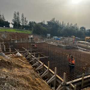 Construction site with foundation work and equipment, surrounded by buildings.