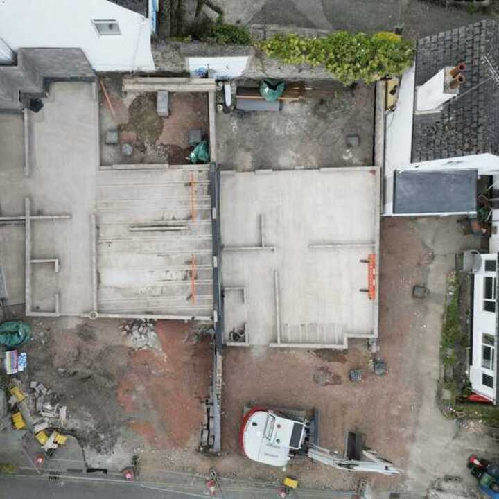Aerial view of a construction site with exposed foundations and surrounding buildings.