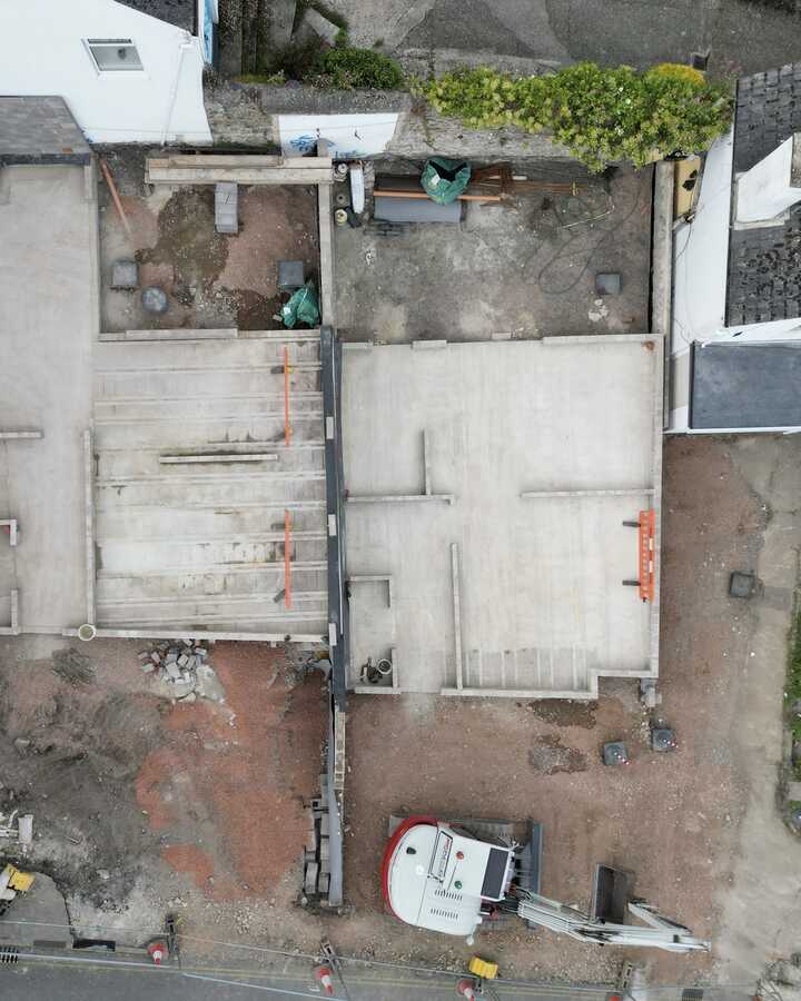 Aerial view of a construction site with unfinished concrete slabs and surrounding buildings.