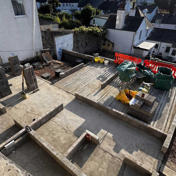 Construction site with foundation work and equipment, surrounded by buildings.