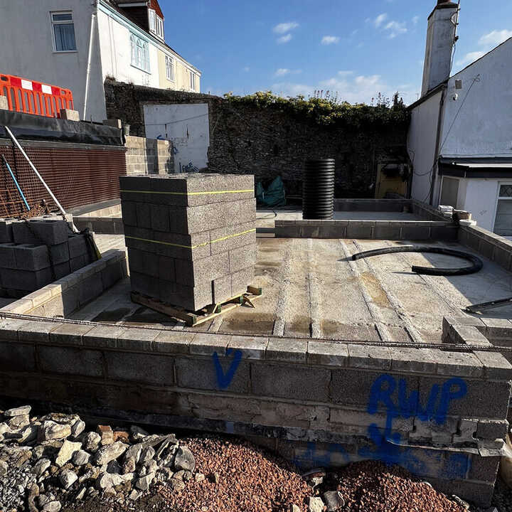 Construction site with gray concrete blocks and a partially completed foundation.