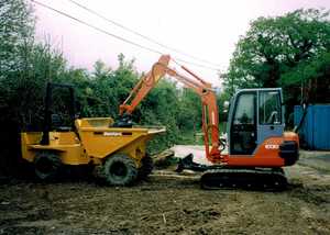 Excavator fills up a dumper truck while clearing ground