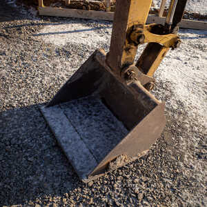 Close-up of an excavator bucket resting on gravel.
