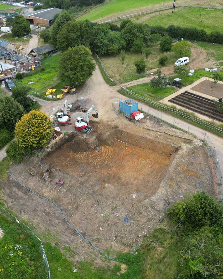Aerial view of a cleared area near farm buildings and gardens.