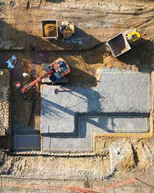 Construction site showing a concrete foundation in progress from above.