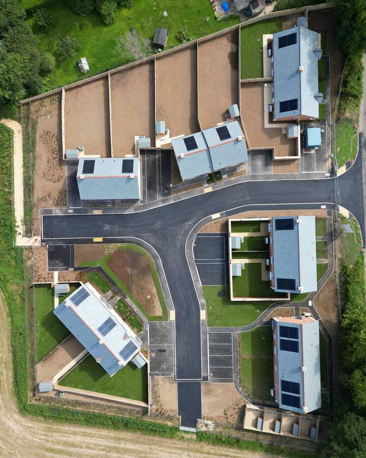 Aerial view of a residential development with several houses and surrounding land.