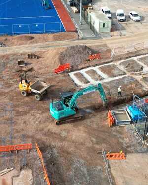 Construction site with two excavators and marked areas for work.