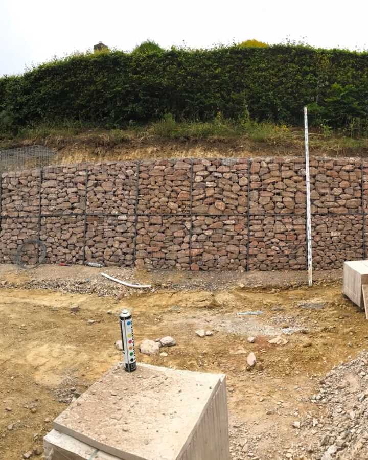 Construction site with stacked bricks and earthworks under clear blue sky.