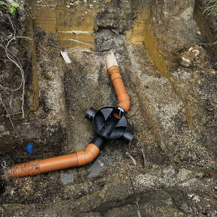 Excavated ground showing orange drainage pipes and a black fitting.