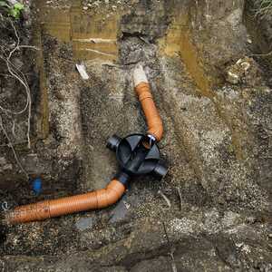 Excavated ground showing orange drainage pipes and a black fitting.