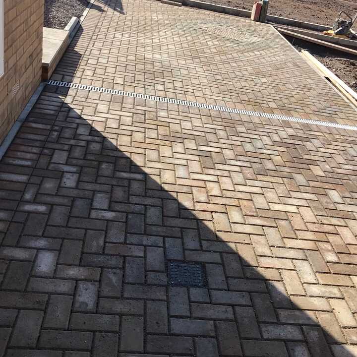 Paved pathway with sunlight, construction site in the background.