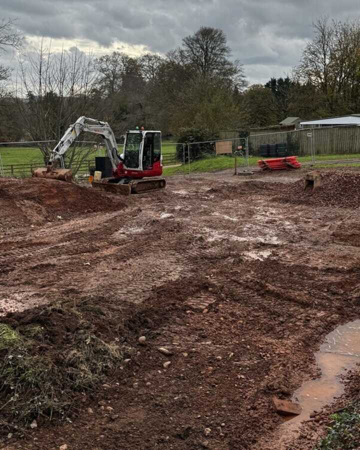 Construction site with excavated ground and machinery in a rural area.