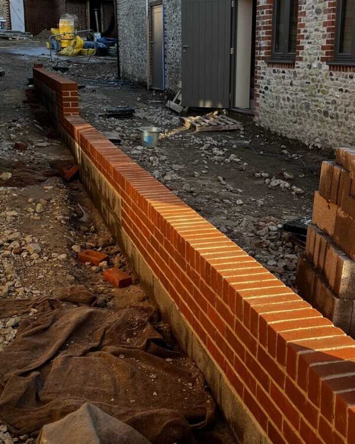 A partially built brick wall along a construction site pathway.